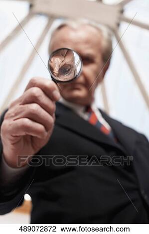Low angle view of a businessman holding a magnifying glass View Large Photo Image Stock Image - Low angle view of a businessman holding a magnifying glass. Fotosearch