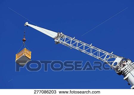 Stock Image - Low angle view of a crane picking up a box. Fotosearch