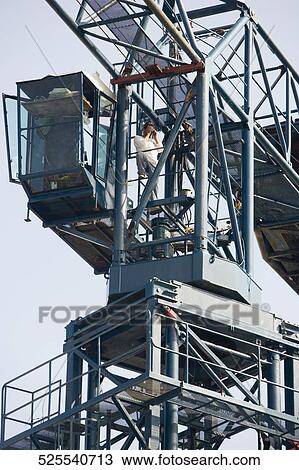 Stock Image - Low angle view of a man working at a construction site. Fotosearch