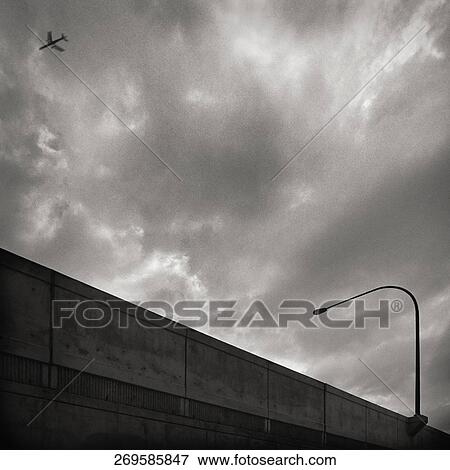 Low angle view of an airplane flying in the cloudy sky View Large Photo Image Stock Photo - Low angle view of an airplane flying in the cloudy sky. Fotosearch