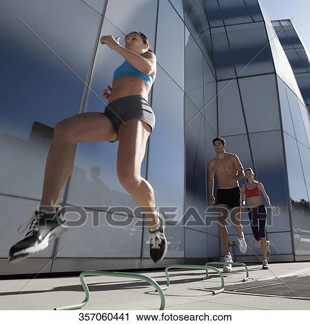 Low angle view of man and two women hurdling View Large Photo Image Stock Image - Low angle view of man and two women hurdling. Fotosearch