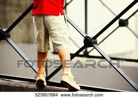 Low section view of a boy leaning against a railing View Large Photo Image Picture - Low section view of a boy leaning against a railing. Fotosearch
