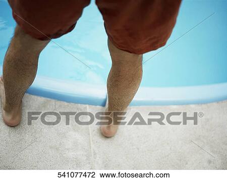 Stock Image - Low section view of a man standing at the poolside. Fotosearch