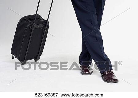 Low section view of a man standing with a suitcase View Large Photo Image Stock Photo - Low section view of a man standing with a suitcase. Fotosearch