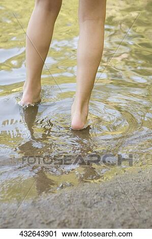 Low section view of a person walking through a puddle View Large Photo Image Stock Image - Low section view of a person walking through a puddle. Fotosearch