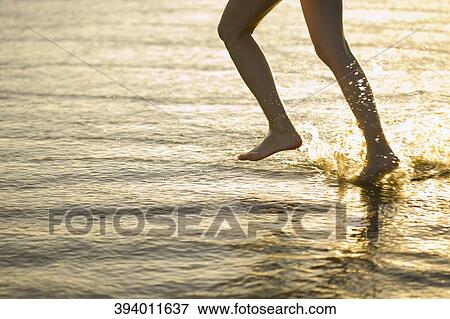 Stock Photo - Low section view of a woman running on the beach. Fotosearch