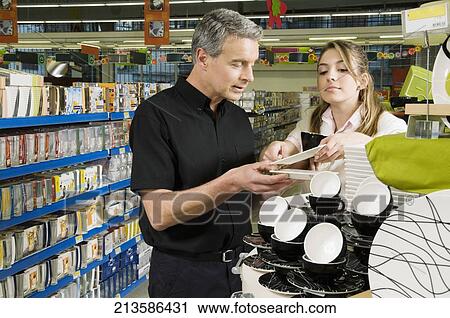 Stock Image - Man and his daughter buying crockery in a supermarket. Fotosearch