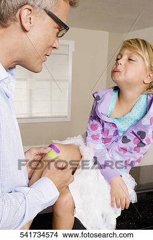 Man applying bandage on his daughter's knee View Large Photo Image Picture - Man applying bandage on his daughter's knee. Fotosearch