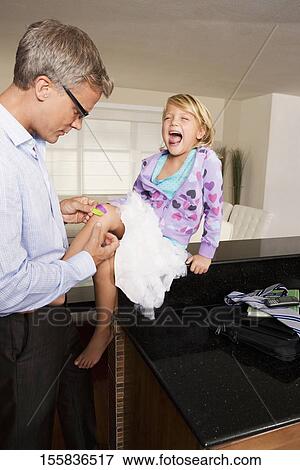 Man applying bandage on his daughter's knee View Large Photo Image Stock Photo - Man applying bandage on his daughter's knee. Fotosearch