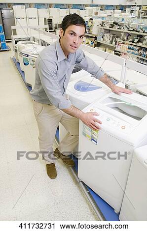 Stock Image - Man buying washing machine in a supermarket. Fotosearch