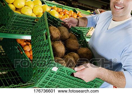 Man carrying a crate of coconuts in a supermarket View Large Photo Image Stock Image - Man carrying a crate of coconuts in a supermarket. Fotosearch