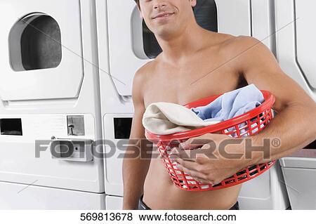 Man carrying a laundry basket in a laundromat View Large Photo Image Stock Photo - Man carrying a laundry basket in a laundromat. Fotosearch