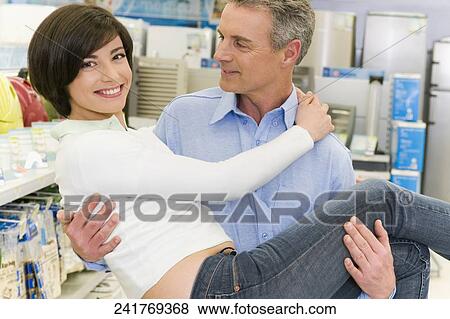 Stock Photo - Man carrying a woman in a supermarket. Fotosearch