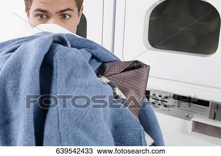 Stock Image - Man carrying clothes in a laundromat. Fotosearch