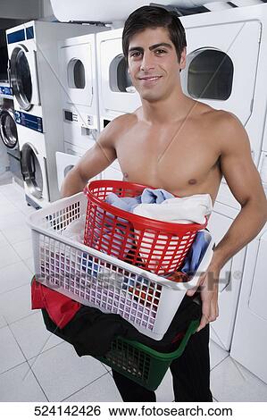Stock Photograph - Man carrying laundry baskets in a laundromat. Fotosearch