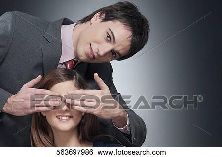 Man covering a woman's eyes and smiling View Large Photo Image Stock Photograph - Man covering a woman's eyes and smiling. Fotosearch