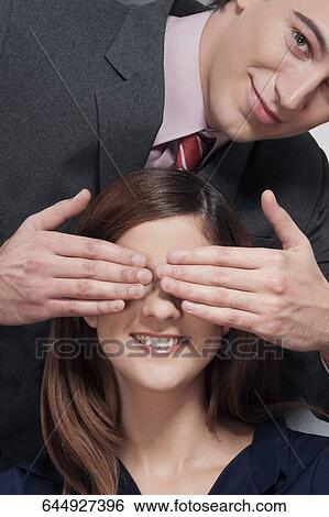 Man covering a woman's eyes and smiling View Large Photo Image Stock Photograph - Man covering a woman's eyes and smiling. Fotosearch