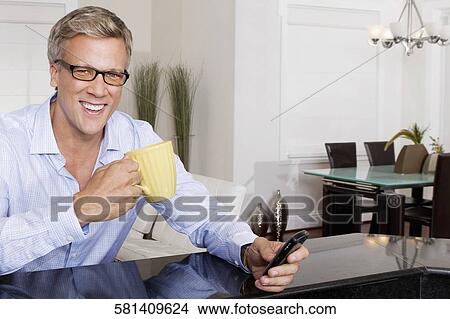 Man drinking coffee and text messaging on a mobile phone View Large Photo Image Picture - Man drinking coffee and text messaging on a mobile phone. Fotosearch