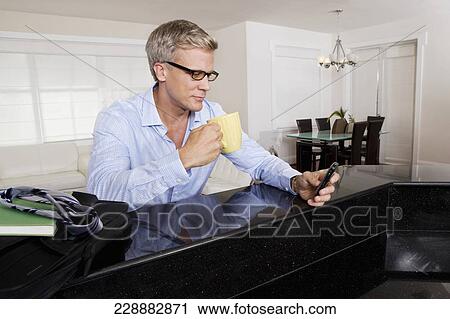 Man drinking coffee and text messaging on a mobile phone View Large Photo Image Stock Image - Man drinking coffee and text messaging on a mobile phone. Fotosearch