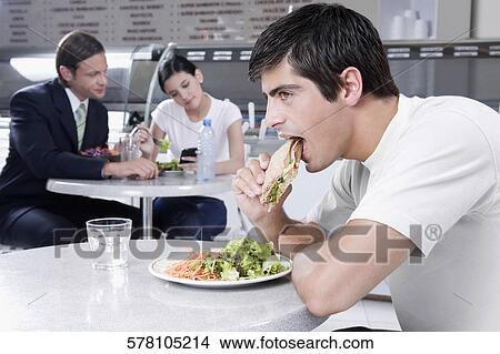 Man eating a sandwich in a restaurant View Large Photo Image Picture - Man eating a sandwich in a restaurant. Fotosearch