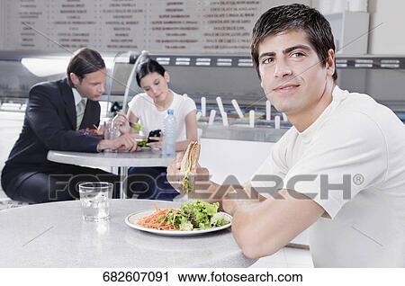 Stock Image - Man eating a sandwich in a restaurant. Fotosearch