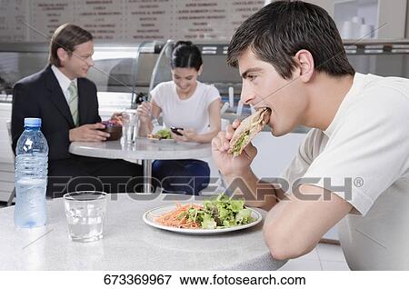 Man eating a sandwich in a restaurant View Large Photo Image Stock Photo - Man eating a sandwich in a restaurant. Fotosearch