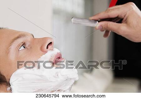 Picture - Man getting shaved in a salon. Fotosearch