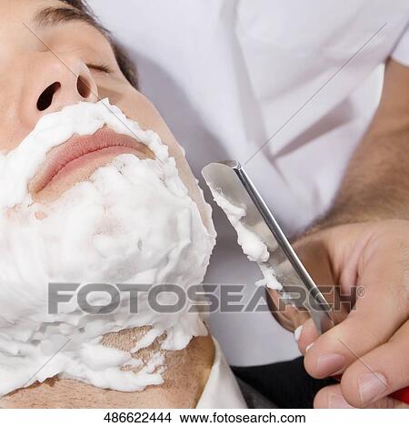 Picture - Man getting shaved in a salon. Fotosearch