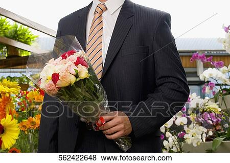 Man holding a bouquet of flowers View Large Photo Image Stock Photo - Man holding a bouquet of flowers. Fotosearch