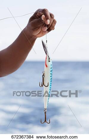 Picture - Man holding a fishing bait. Fotosearch
