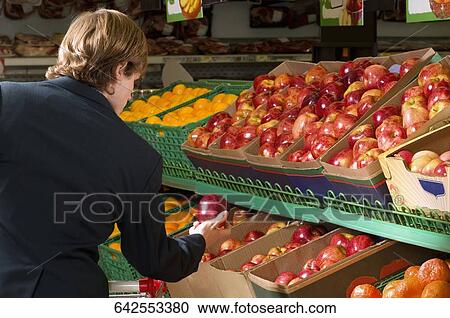 Man holding an apple in a supermarket View Large Photo Image Stock Image - Man holding an apple in a supermarket. Fotosearch