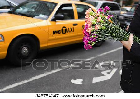 Stock Photo - Man holding bunch of flowers in a market, 28 Street, New York City, New York State, USA. Fotosearch
