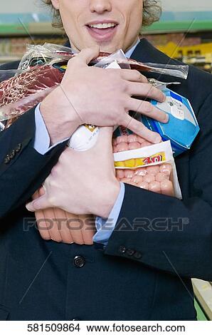 Picture - Man holding meat packets in a supermarket. Fotosearch