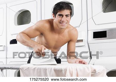 Stock Image - Man ironing in a laundromat. Fotosearch