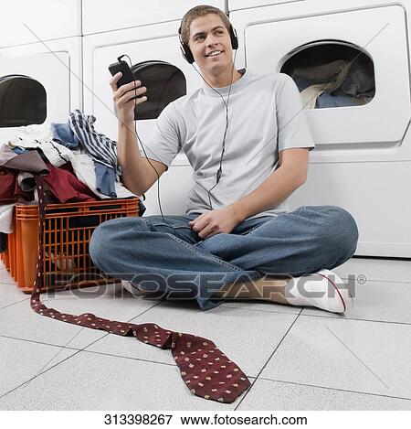 Stock Photo - Man listening to an MP3 player in a laundromat. Fotosearch