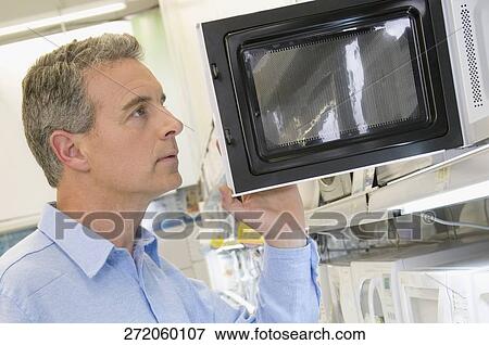 Man looking at a microwave oven in a supermarket View Large Photo Image Stock Photo - Man looking at a microwave oven in a supermarket. Fotosearch