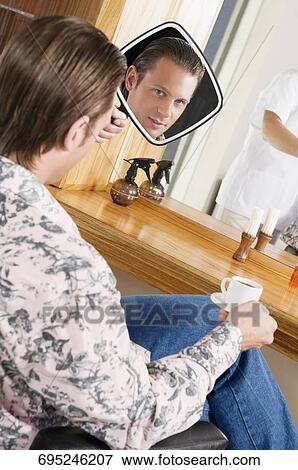 Man looking himself in a mirror after a haircut View Large Photo Image Stock Photo - Man looking himself in a mirror after a haircut. Fotosearch
