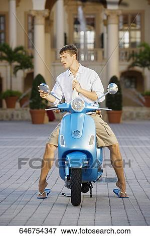 Stock Photo - Man looking into a moped mirror, Biltmore Hotel, Coral Gables, Florida, USA. Fotosearch