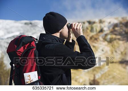 Man looking through binoculars, Mammoth Hot Springs, Yellowstone National Park, Wyoming, USA View Large Photo Image Stock Image - Man looking through binoculars, Mammoth Hot Springs, Yellowstone National Park, Wyoming, USA. Fotosearch