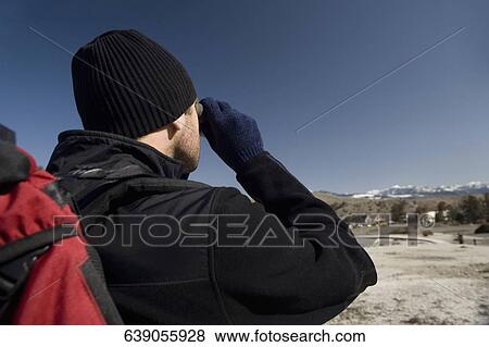 Stock Photo - Man looking through binoculars, Mammoth Hot Springs, Yellowstone National Park, Wyoming, USA. Fotosearch