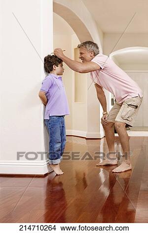 Man measuring his son's height View Large Photo Image Picture - Man measuring his son's height. Fotosearch