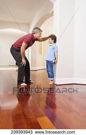 Man measuring his son's height View Large Photo Image Stock Image - Man measuring his son's height. Fotosearch