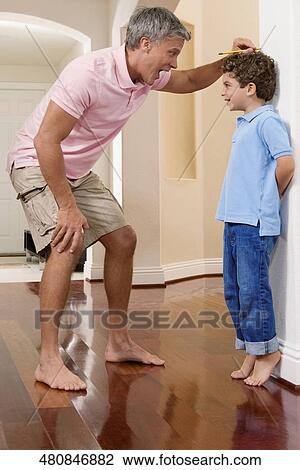 Man measuring his son's height View Large Photo Image Stock Image - Man measuring his son's height. Fotosearch