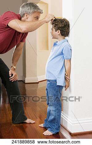 Man measuring his son's height View Large Photo Image Stock Photo - Man measuring his son's height. Fotosearch