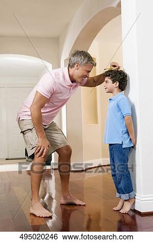 Man measuring his son's height View Large Photo Image Stock Photograph - Man measuring his son's height. Fotosearch
