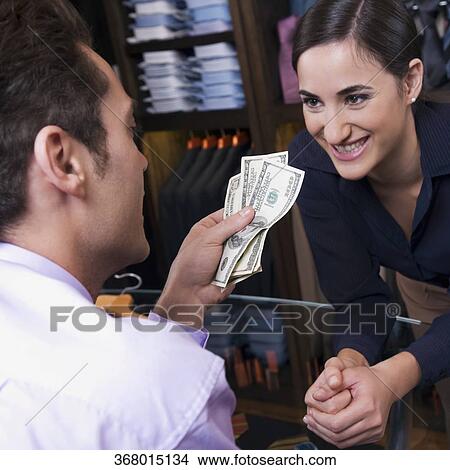 Man paying to a sales clerk in a clothing store View Large Photo Image Picture - Man paying to a sales clerk in a clothing store. Fotosearch