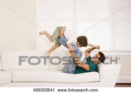 Man playing with his son on a couch View Large Photo Image Stock Image - Man playing with his son on a couch. Fotosearch