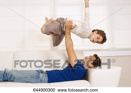 Man playing with his son on a couch View Large Photo Image Stock Image - Man playing with his son on a couch. Fotosearch