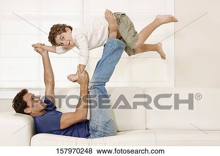 Man playing with his son on a couch View Large Photo Image Stock Photo - Man playing with his son on a couch. Fotosearch