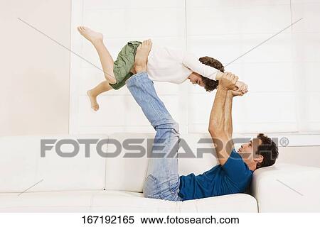 Man playing with his son on a couch View Large Photo Image Stock Photography - Man playing with his son on a couch. Fotosearch